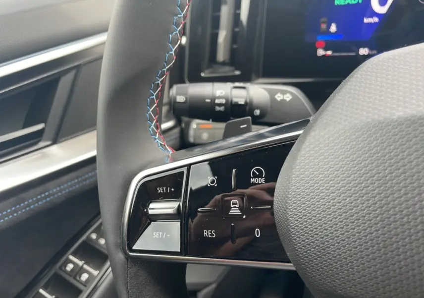 Gros plan sur le volant cuir multifonctions du Renault Austral New 200 Esprit Alpine, avec surpiqûres bleues et rouges.