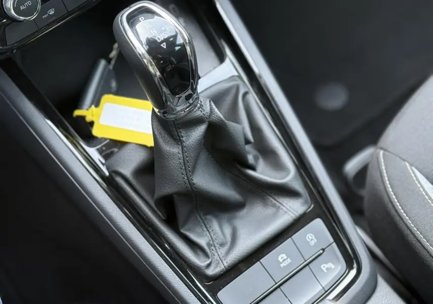 Gros plan sur le levier de vitesses automatique noir et chrome de la Skoda Scala TSI 116 DSG7 Sélection, intérieur gris.