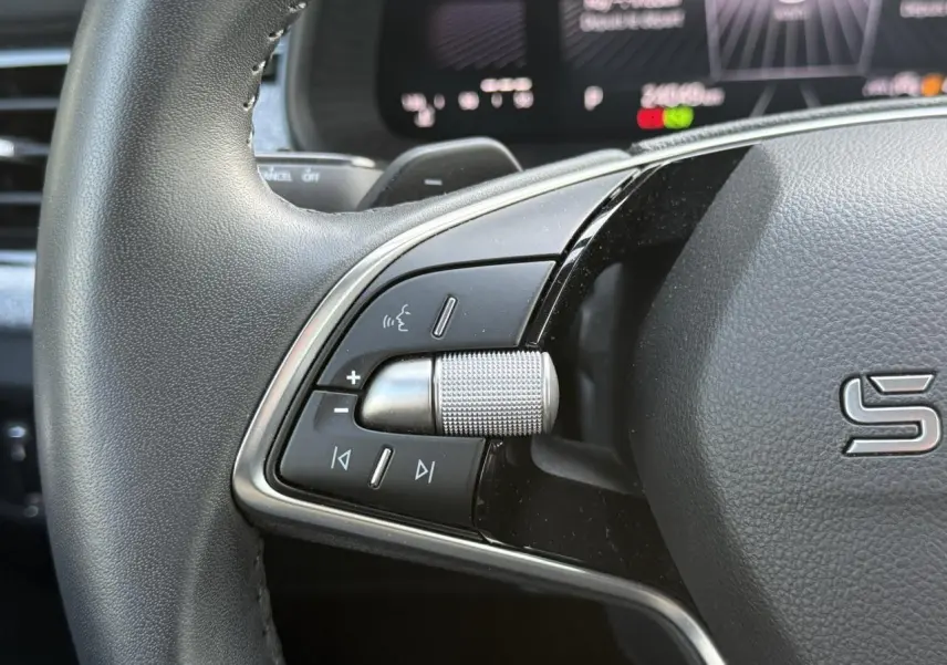 Gros plan sur la partie gauche du volant cuir noir du Skoda Scala 2025 avec commandes multifonctions et molette métallique.