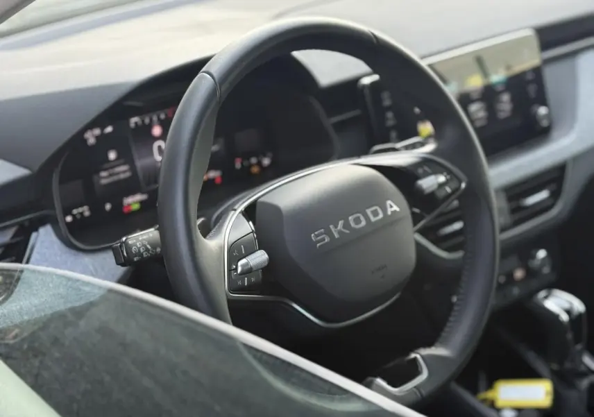 Vue rapprochée du volant en cuir noir multifonctions d’une Skoda Scala 2025, avec tableau de bord digital en arrière-plan.