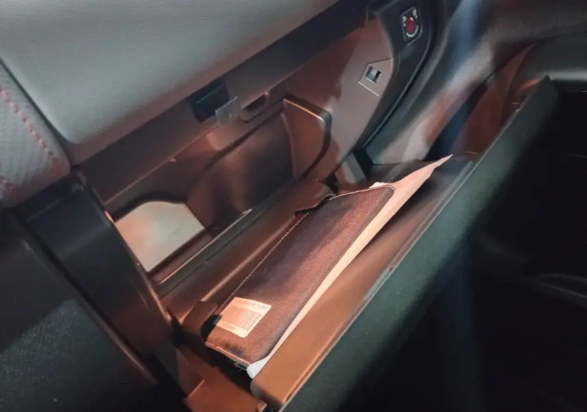 Gros plan de la boîte à gants ouverte du Citroën C5 Aircross blanc 2020, montrant un manuel dans un étui noir.