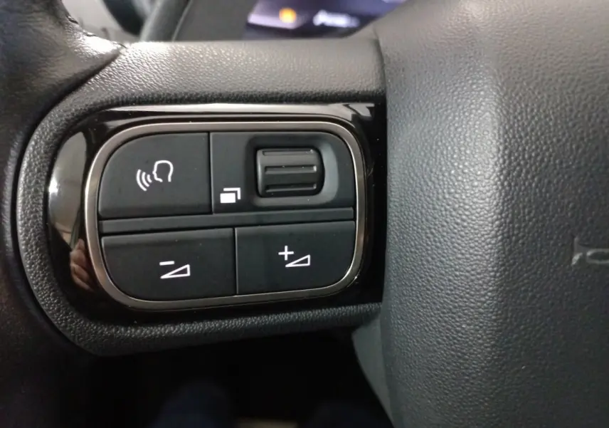 Gros plan sur les commandes vocales et volume sur le volant cuir noir du Citroën C5 Aircross blanc 2020.