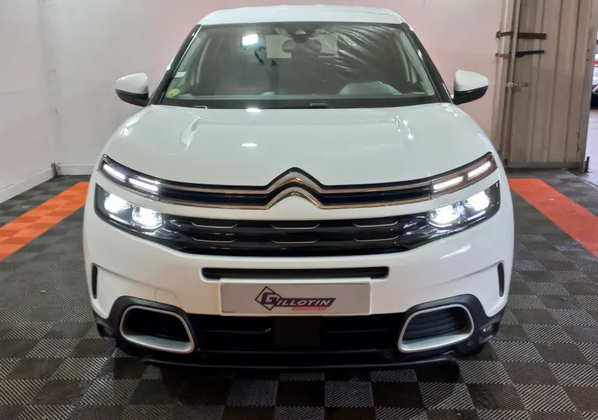 Vue frontale d'un Citroën C5 Aircross blanc avec phares LED allumés et calandre noire distinctive.