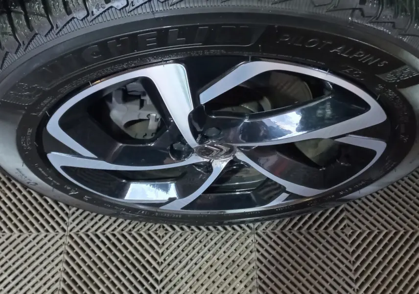 Gros plan sur la jante noire et argentée d'un Citroën C5 Aircross blanc, mettant en valeur le logo central et le pneu Michelin.