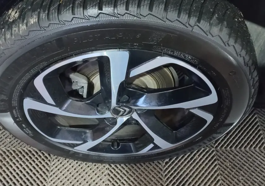 Gros plan sur la jante noire et argentée avec logo Citroën d'un Citroën C5 Aircross blanc, vue latérale.