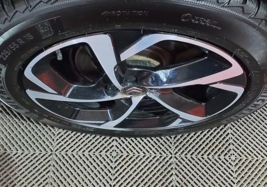 Gros plan sur la jante noire et argentée d'une Citroën C5 Aircross blanche, mettant en valeur le logo central distinctif.