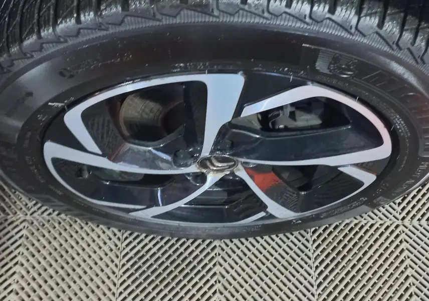 Gros plan sur la jante noire et argentée d'une Citroën C5 Aircross blanche, mettant en valeur le logo central Citroën.