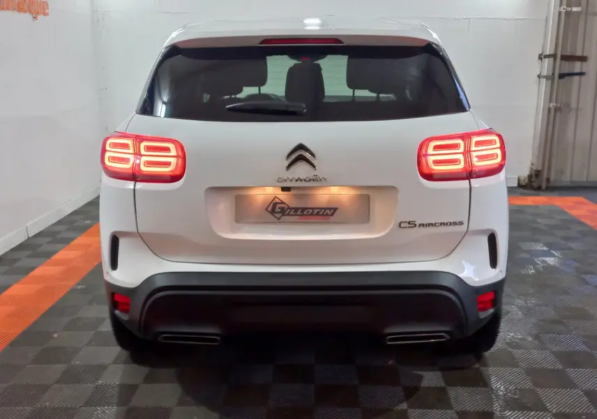 Vue arrière d'un Citroën C5 Aircross blanc avec feux arrière allumés dans un garage intérieur.