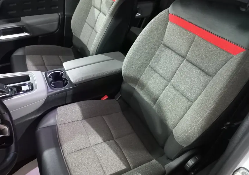 Vue intérieure rapprochée des sièges avant gris avec bande rouge sur appuie-tête du Citroën C5 Aircross blanc.