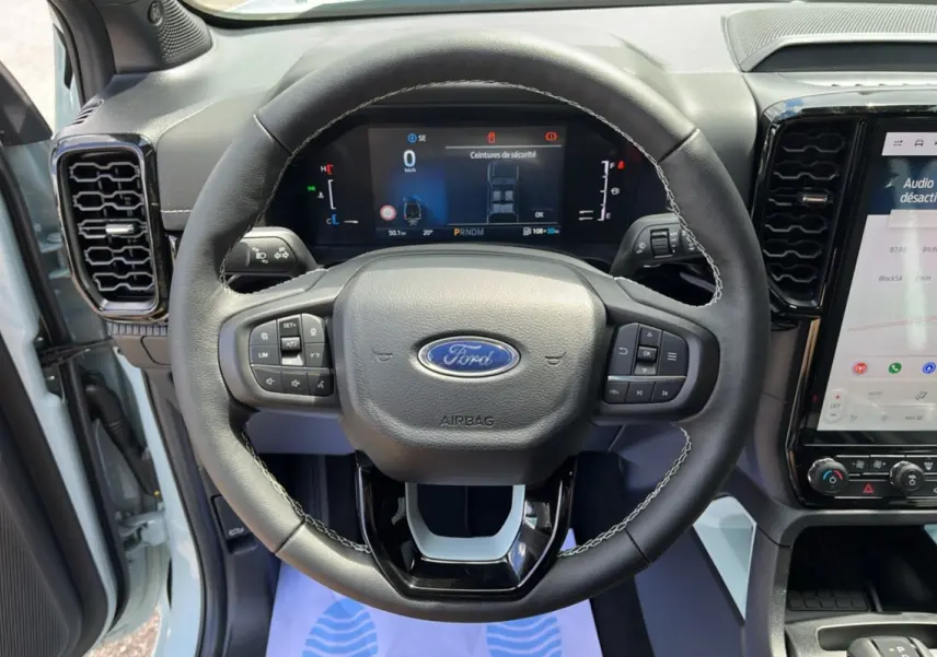 Vue rapprochée du volant cuir multifonctions du Ford Ranger gris zen avec tableau de bord digital et écran tactile.