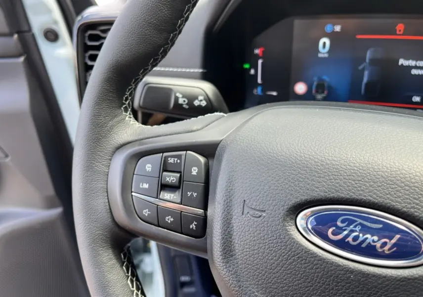 Gros plan sur le volant cuir multifonctions du Ford Ranger gris zen, avec commandes intégrées et tableau de bord numérique en arrière-plan.