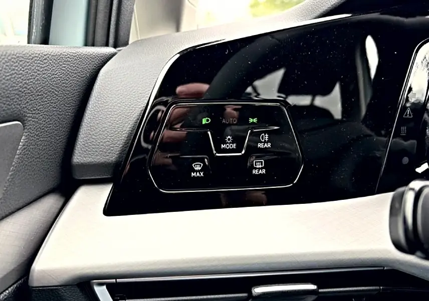 Détail du tableau de bord noir et beige de la Volkswagen Golf 2026, avec commandes d’éclairage et dégivrage.
