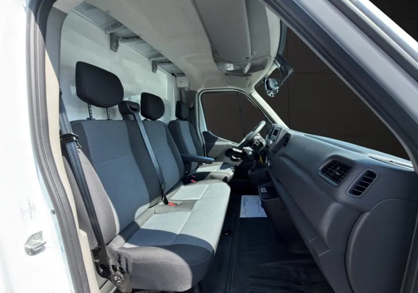 Intérieur du Renault Master 2024 vu côté conducteur, montrant les sièges gris et le tableau de bord noir.