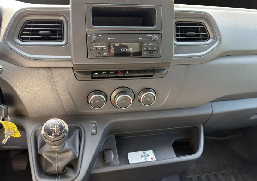 Vue rapprochée de la console centrale noire du Renault Master 2024 avec levier de vitesse manuel et commandes climatisation.