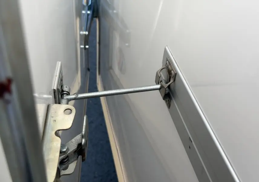 Détail du mécanisme d’ouverture métallique sur la porte arrière blanche du Renault Master 2024.