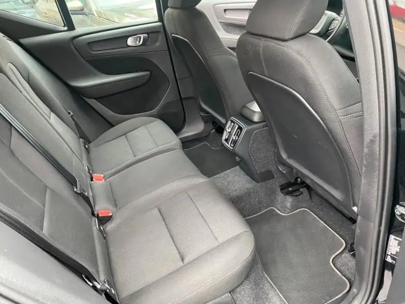 Vue intérieure arrière côté droit du Volvo XC40 T3 2020 avec sièges et garnitures en tissu noir et aérateurs centraux.