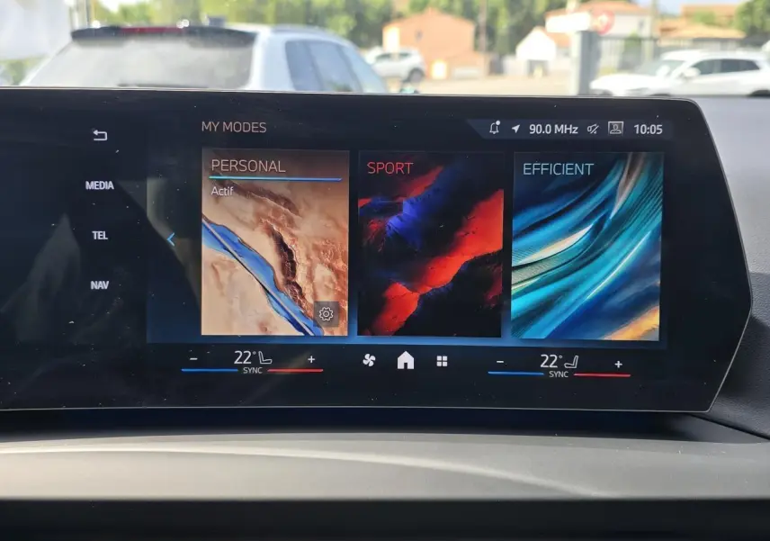 Écran incurvé BMW Live Cockpit affichant les modes de conduite Personal, Sport et Efficient dans une BMW Série 1 2024.