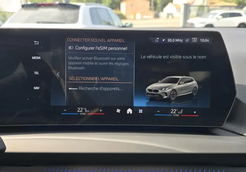 Écran incurvé BMW Live Cockpit affichant une BMW Série 1 gris Skyscraper vue en 3/4 avant droit.