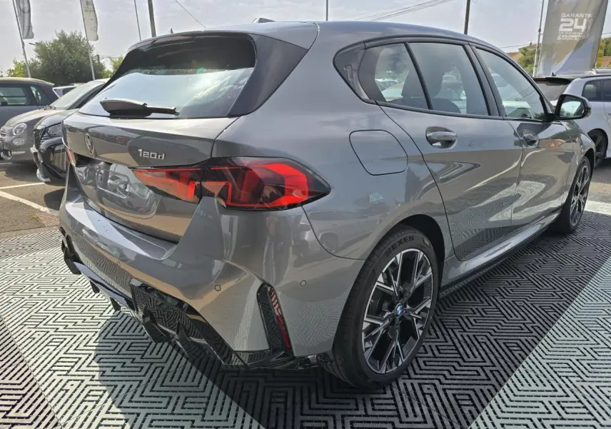 BMW Série 1 120d gris Skyscraper vue 3/4 arrière droit avec jantes M Sport et feux arrière LED distinctifs.