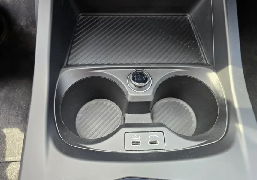 Gros plan sur la console centrale noire de la BMW Série 1 120D M Sport avec deux porte-gobelets et deux ports USB-C.