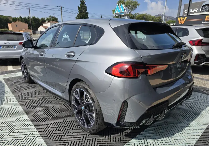BMW Série 1 120d M Sport gris Skyscraper vue 3/4 arrière droit avec jantes 18 pouces et feux LED distinctifs.