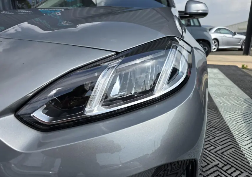 Gros plan sur le phare avant droit d'une BMW Série 1 120D 2024 en gris Skyscraper métallisé.