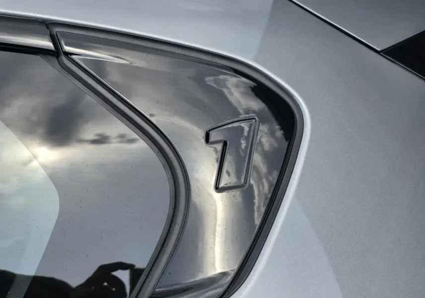 Détail du logo "1" sur la vitre arrière droite de la BMW Série 1 gris Skyscraper métallisé.