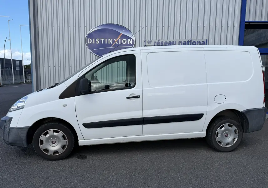 Vue de profil côté gauche d'un FIAT Scudo Fourgon blanc de 2015 avec baguettes latérales noires et jantes acier.