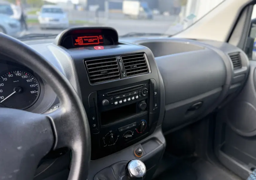 Vue intérieure côté conducteur du tableau de bord noir et levier de vitesses manuel du Fiat Scudo Fourgon blanc de 2015.