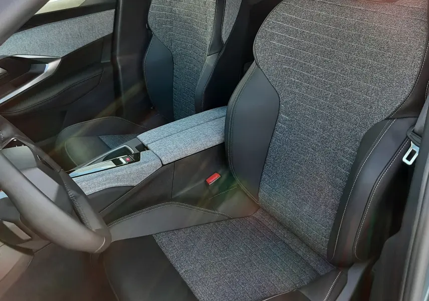 Vue intérieure rapprochée des sièges avant en tissu gris et cuir noir du Peugeot 5008 Bleu Ingaro 2025 hybride.