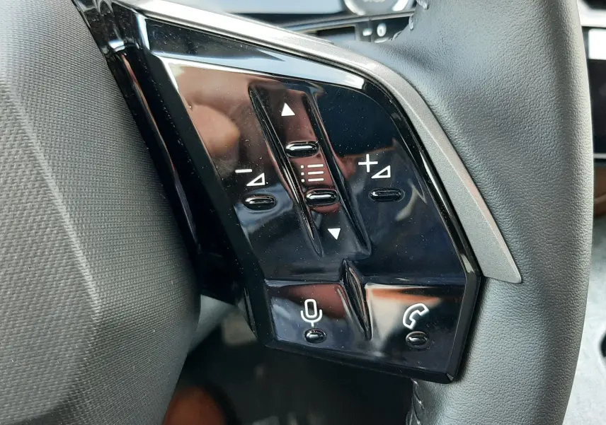 Gros plan sur les commandes vocales et téléphoniques à gauche du volant du Peugeot 5008 bleu Ingaro 2025.
