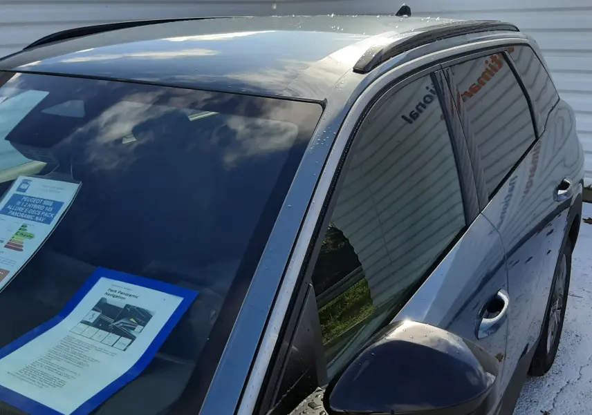 Vue de côté droit avant d'un Peugeot 5008 bleu Ingaro 2025 avec vitres teintées et barres de toit noires.