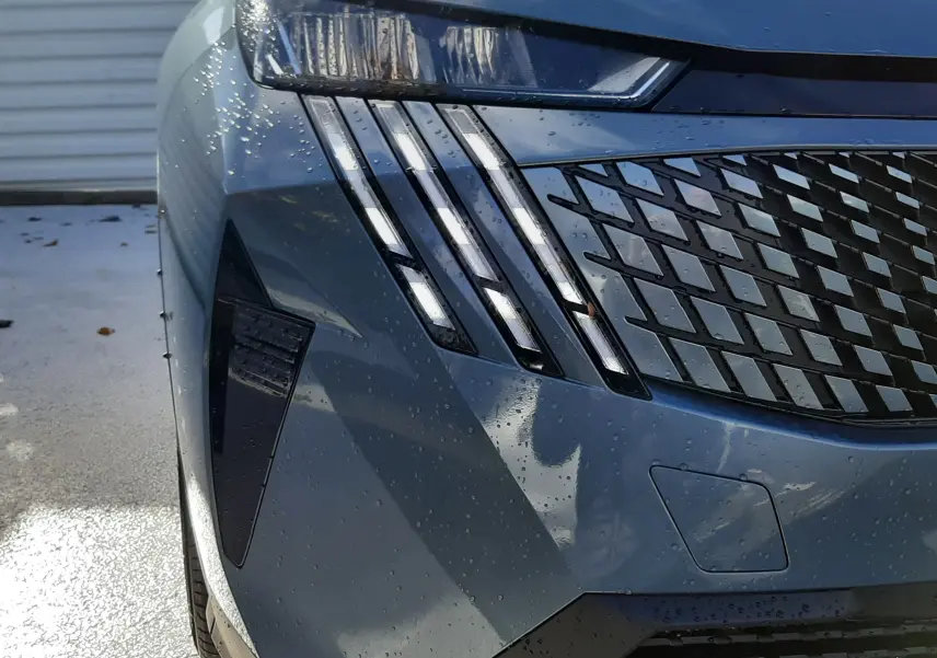 Gros plan sur l'avant gauche du Peugeot 5008 bleu Ingara, mettant en valeur ses phares LED et sa calandre distinctive.