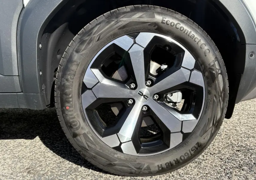 Gros plan sur la jante alliage 18 pouces noire et argent du Dacia Duster blanc métallisé, côté droit arrière.