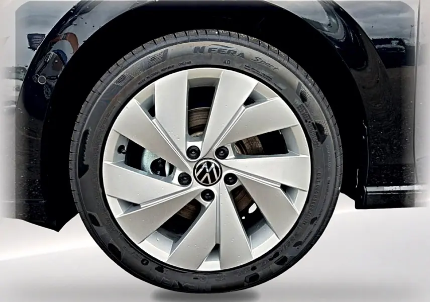 Gros plan sur la roue avant gauche noire d'une Volkswagen Golf 2026 avec jante alu 17 pouces argentée.