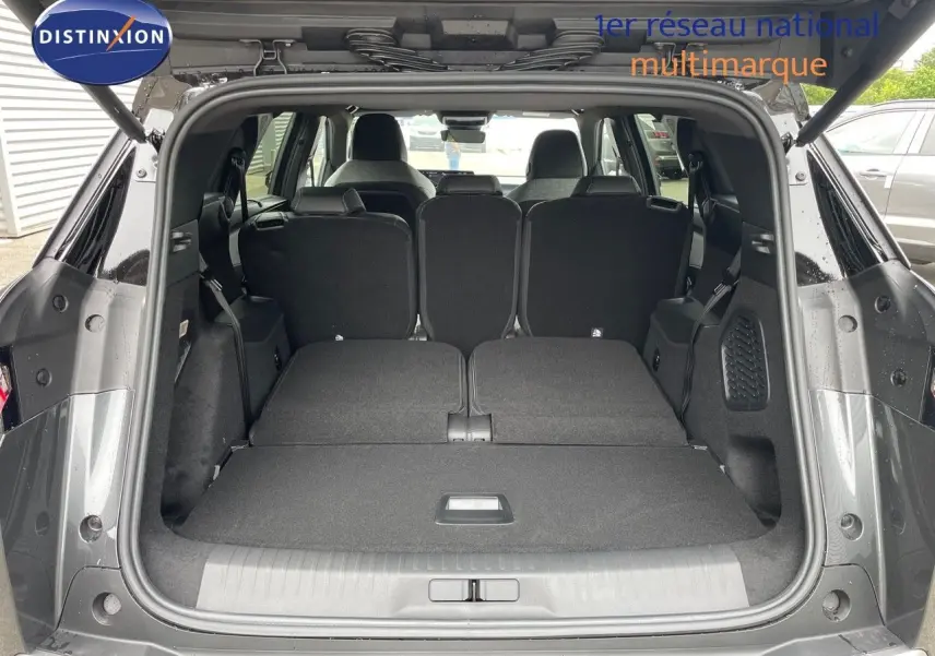 Coffre ouvert d'un Peugeot 5008 gris titane avec sièges arrière rabattus, vue arrière montrant l'espace intérieur.