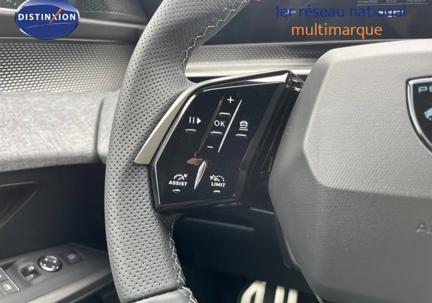 Gros plan sur le volant cuir perforé côté gauche du Peugeot 5008 gris titane avec commandes intégrées.