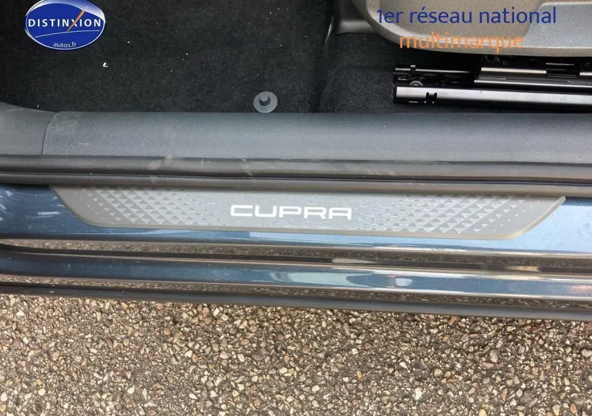 Gros plan sur la plaque de seuil de porte CUPRA gris magnétique côté gauche avec moquette noire intérieure.