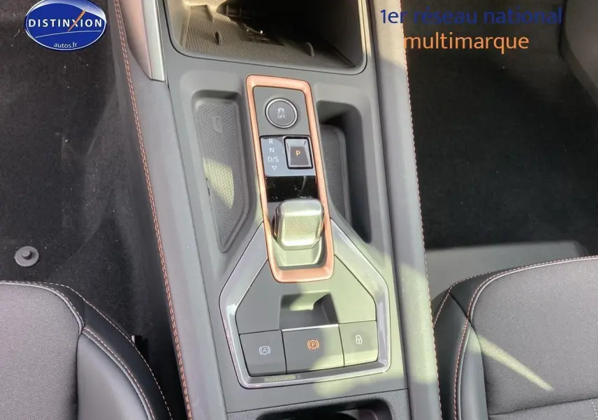 Vue rapprochée de la console centrale du CUPRA Formentor gris magnétique avec levier de vitesse et surpiqûres orange.