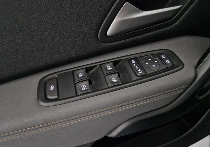 Gros plan sur les commandes de lève-vitres et rétroviseurs côté gauche du Dacia Duster blanc 2024.