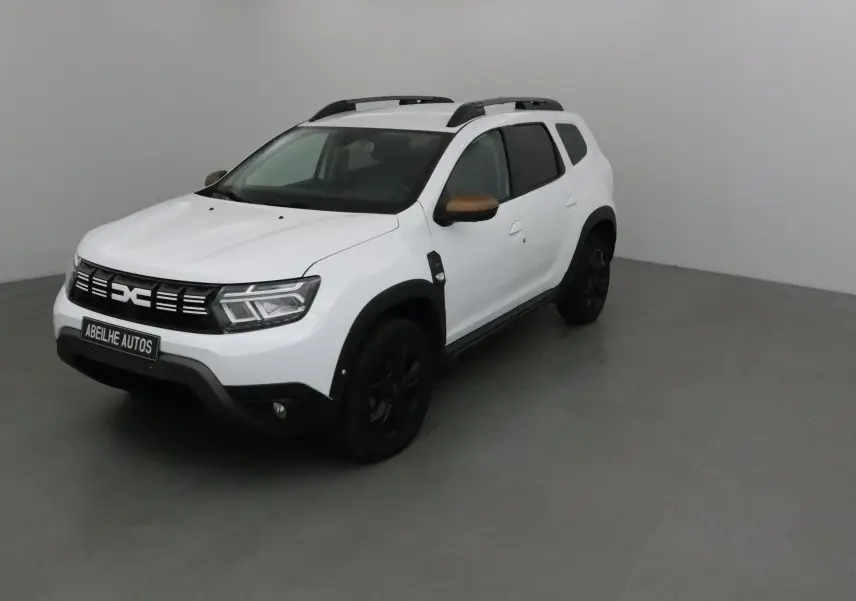 Dacia Duster 4x4 blanc en 3/4 avant droit avec coques de rétroviseurs bronze et jantes noires.