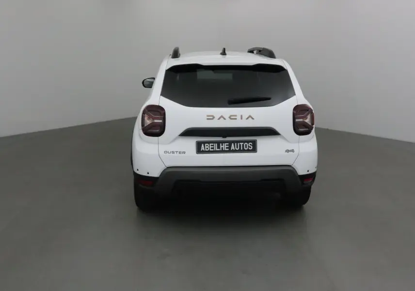 Vue arrière d'un Dacia Duster blanc 4x4 2024 avec logo et plaque Abeilhe Autos visible.
