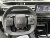 Vue intérieure du poste de conduite de la Citroën C3 1.2 turbo 100 cv Max 2025, volant noir et écran tactile visible.