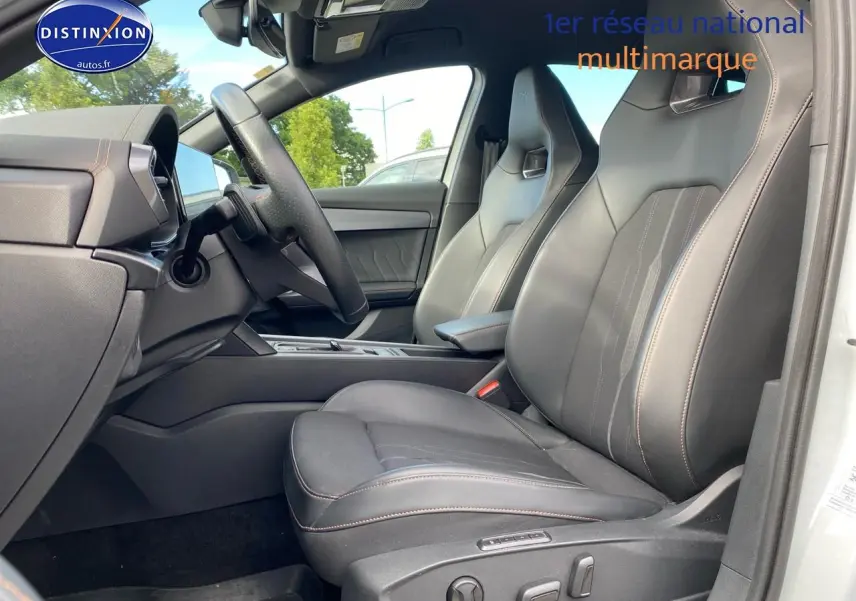 Vue intérieure côté conducteur du CUPRA Formentor blanc 2023, sièges sport en tissu noir avec surpiqûres cuivrées.