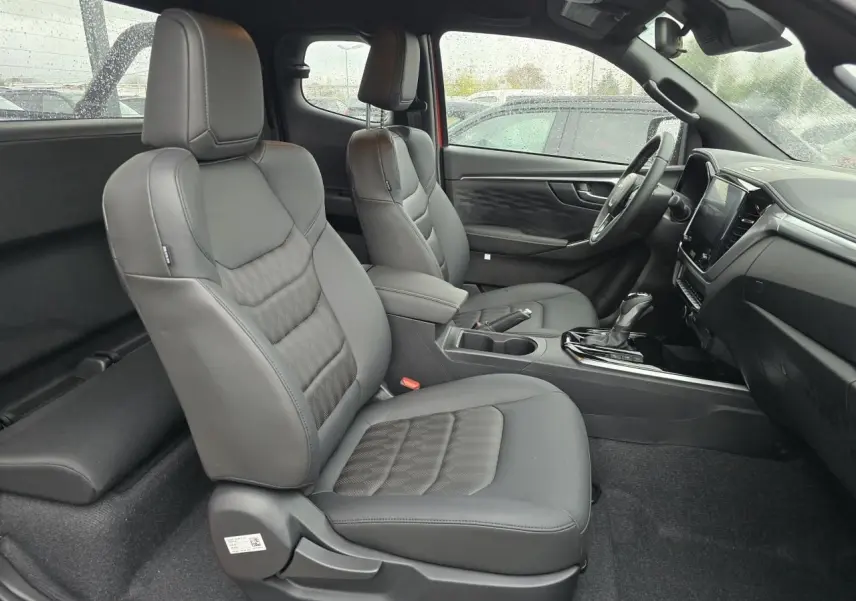 Vue intérieure côté droit du pick-up Isuzu D-MAX 2025 avec sièges en cuir noir et tableau de bord moderne.