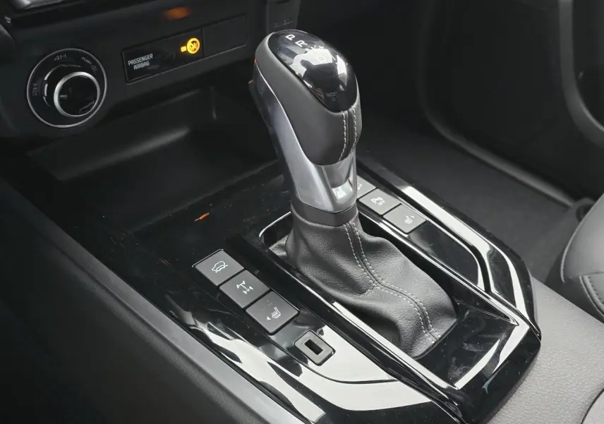 Gros plan sur le levier de vitesse automatique noir et chrome de l'Isuzu D-MAX III NEW 2025 avec commandes 4x4 et sièges cuir.