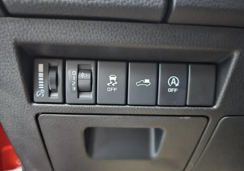 Panneau de commandes intérieures avec réglage luminosité, contrôle phares et aides à la conduite sur Isuzu D-MAX orange.