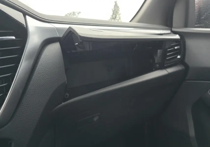 Intérieur du tableau de bord côté passager du pick-up Isuzu D-MAX 2025, avec boîte à gants ouverte et finition noire.