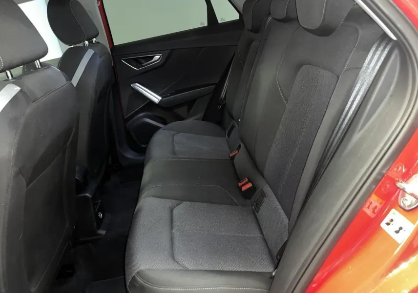 Vue intérieure côté droit des sièges arrière noirs de l'Audi Q2 rouge 2024 finition S line.