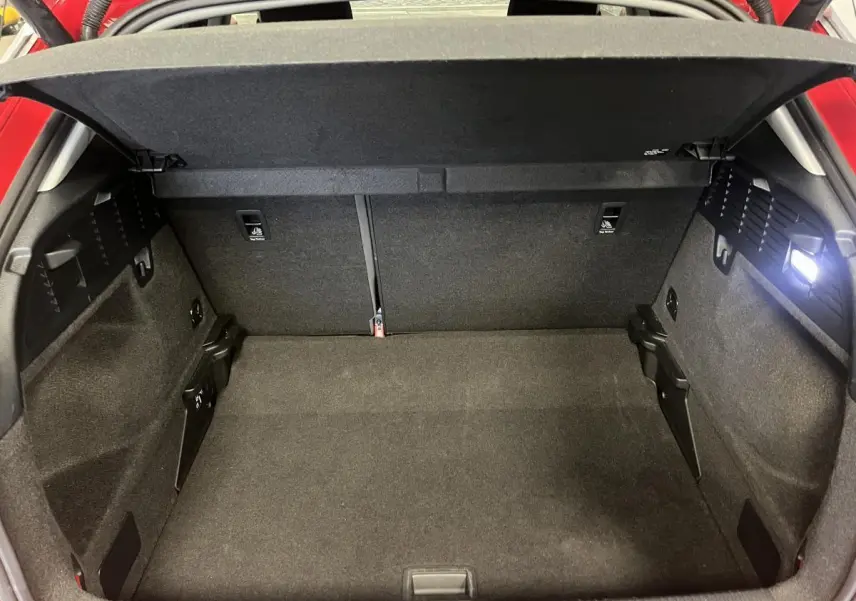 Vue intérieure du coffre ouvert de l'Audi Q2 rouge 2024, montrant un espace de rangement propre et spacieux.